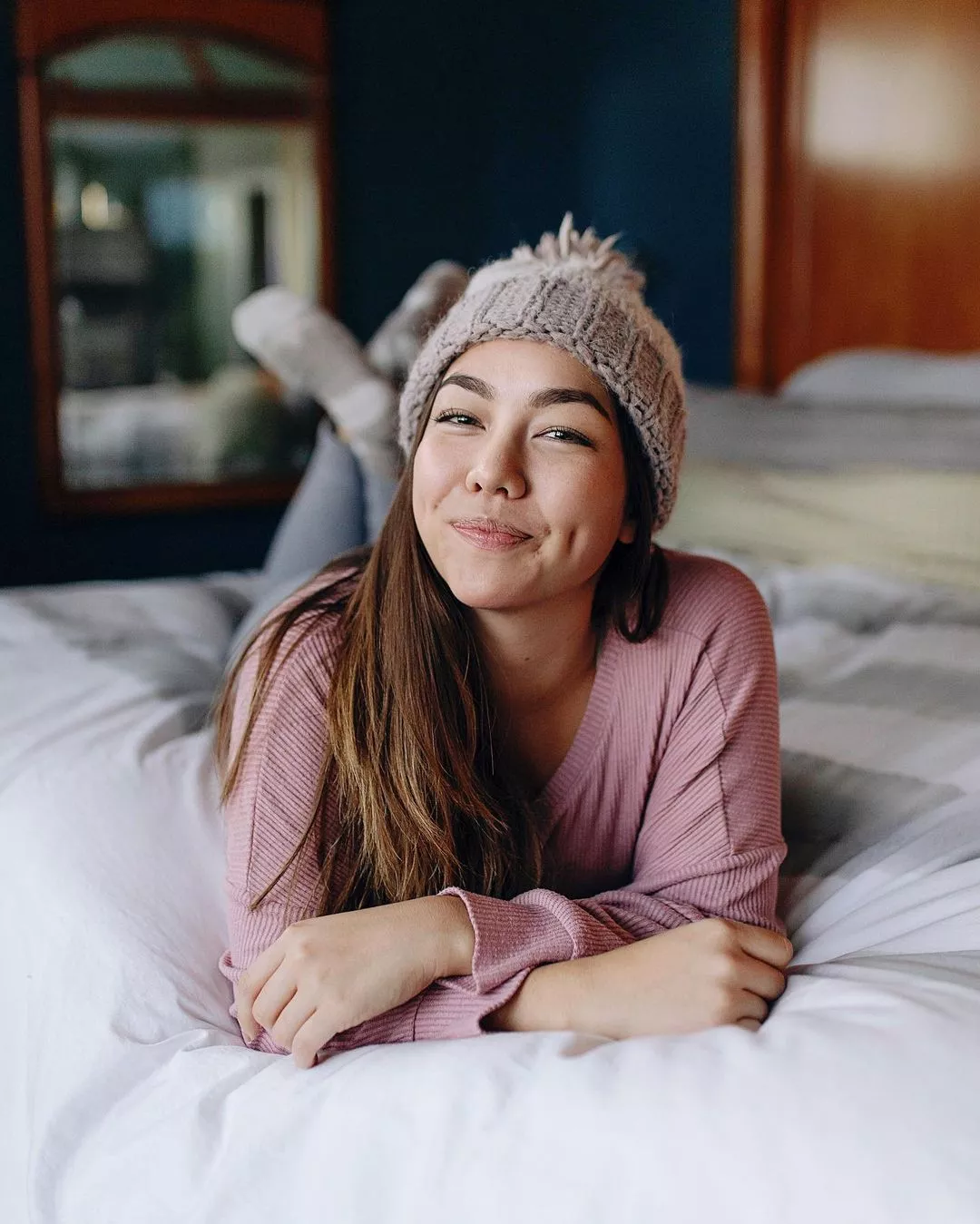 annemari chase posing on a bed annd smiling